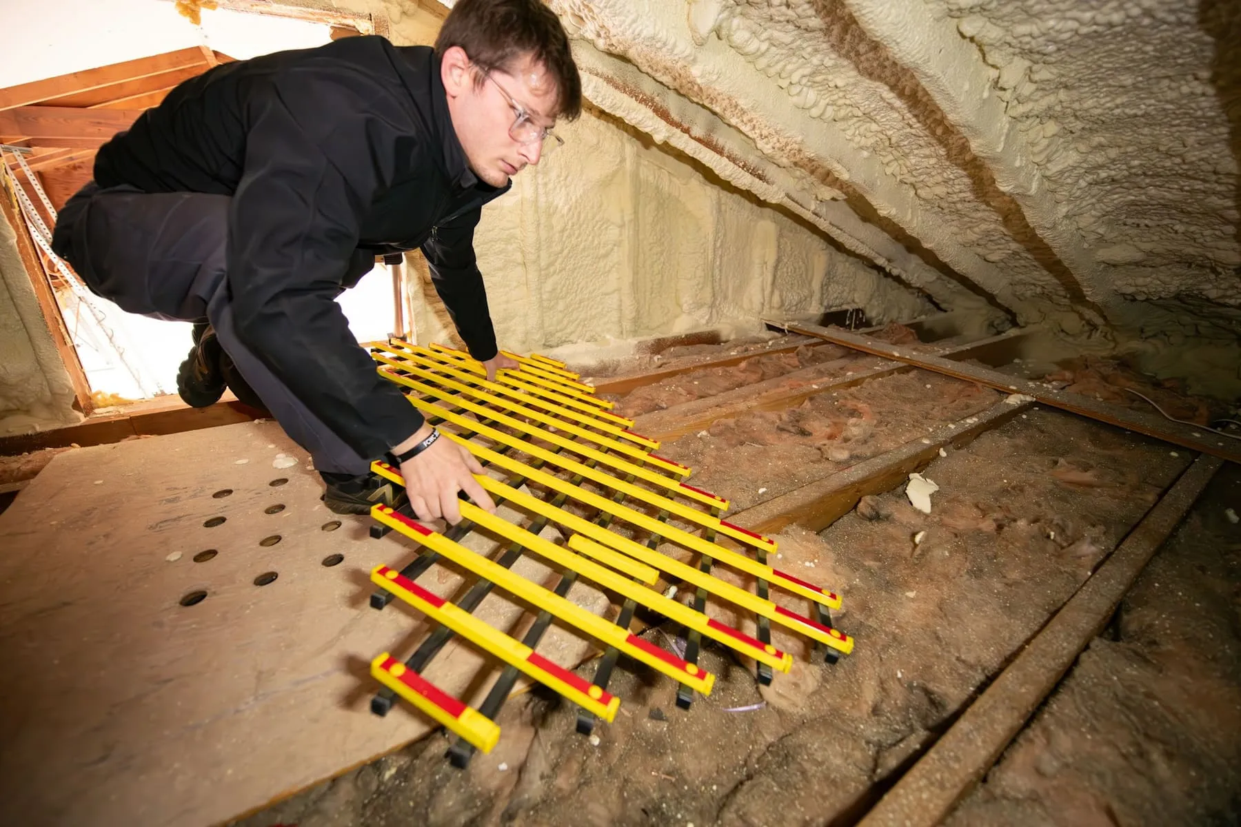 Artisan posant un isolant dans des combles